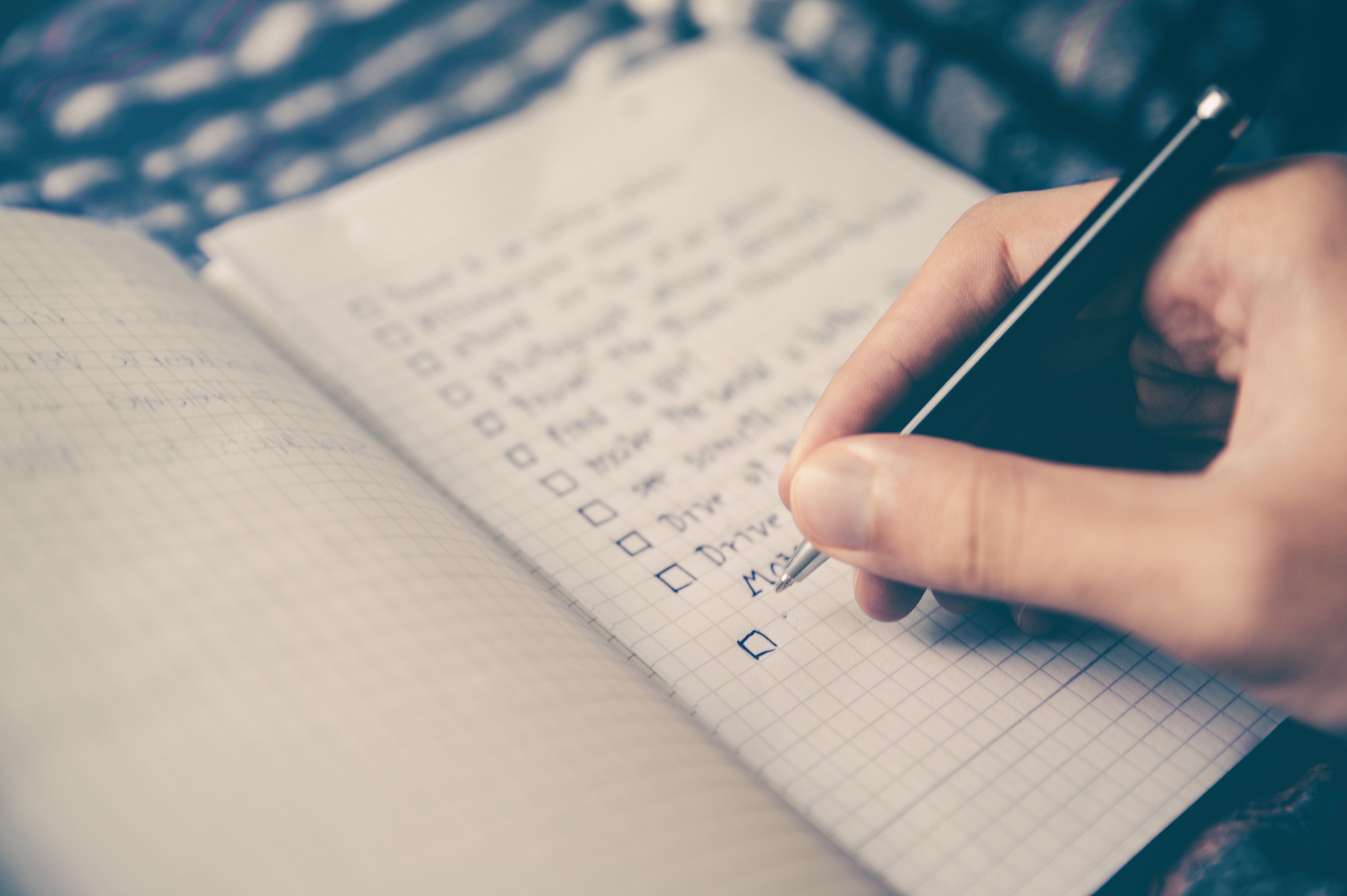 A person making a checklist in a notebook.