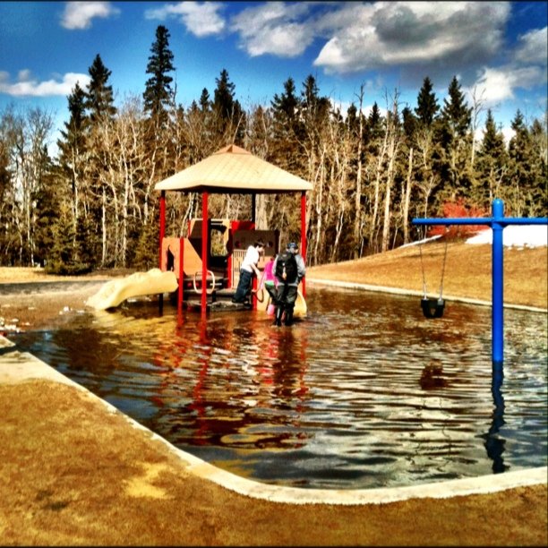 Large pool of standing water is around the equipment.  The playground is the low point next to a small hill. 