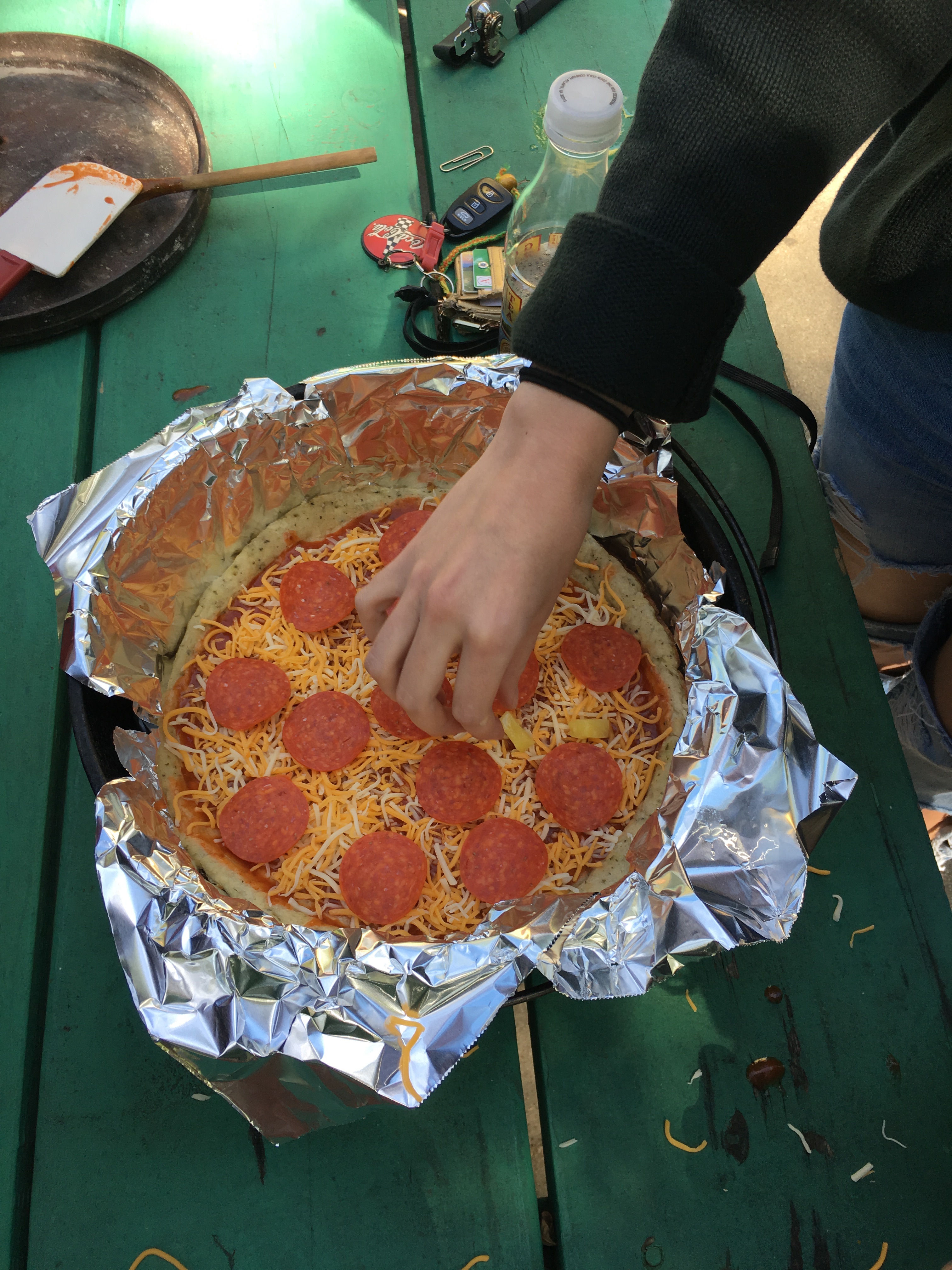 A students' pizza is ready to be cooked. The foil will be tucked inside the oven before cooking.