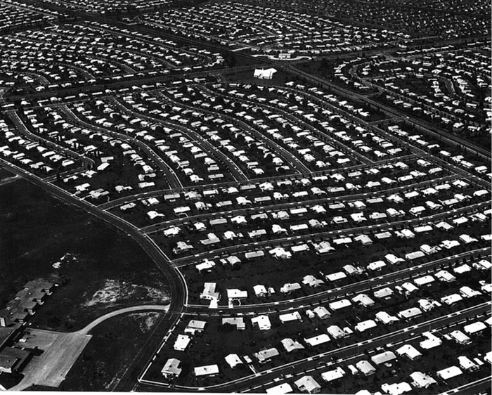 Aerial view of a homogeneous suburban neighborhood shows rows and rows of evenly spaced, identical houses.