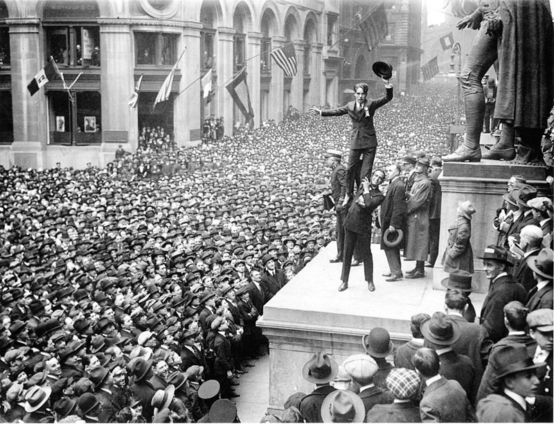 Charlie Chaplin stands on Douglas Fairbanks' shoulders during a Liberty bonds rally. They are at the foot of George Washington’s statue in front of the Sub-Treasury. By Underwood & Underwood (see lens.blogs.nytimes.com) [Public domain], via Wikimedia Commons