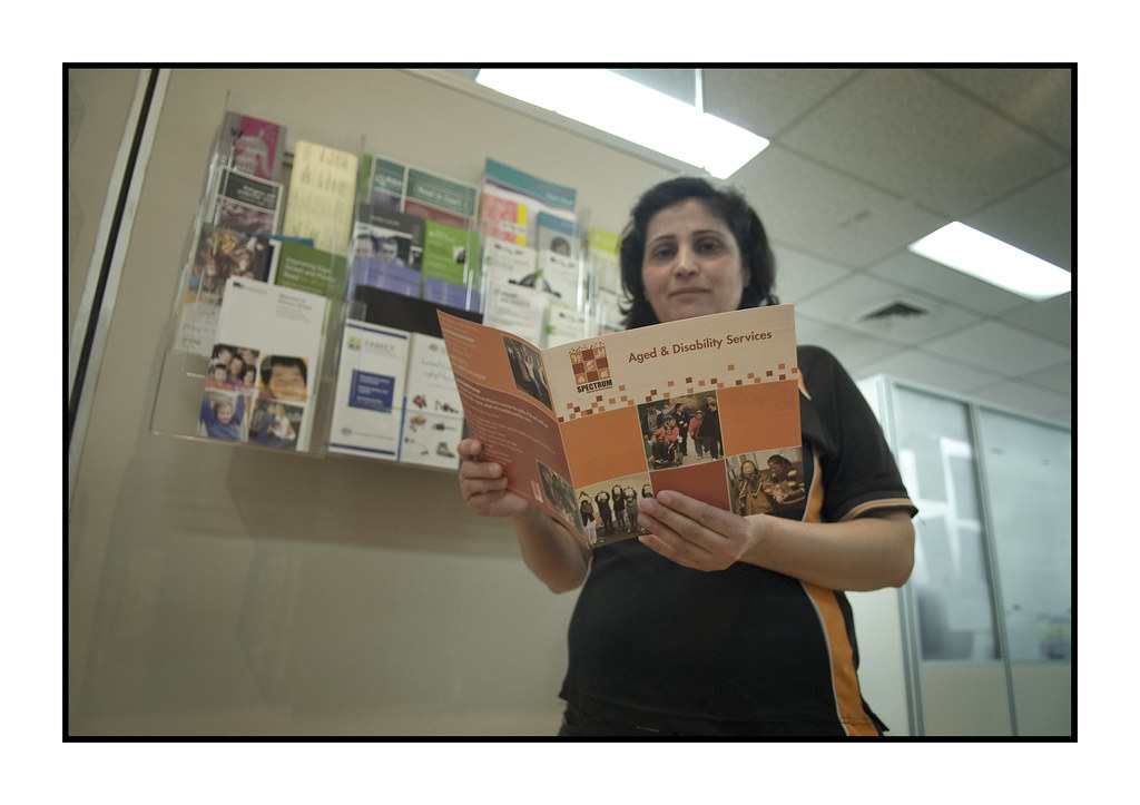 Community Worker holding a service brochure called "Aged and Disability Services."
