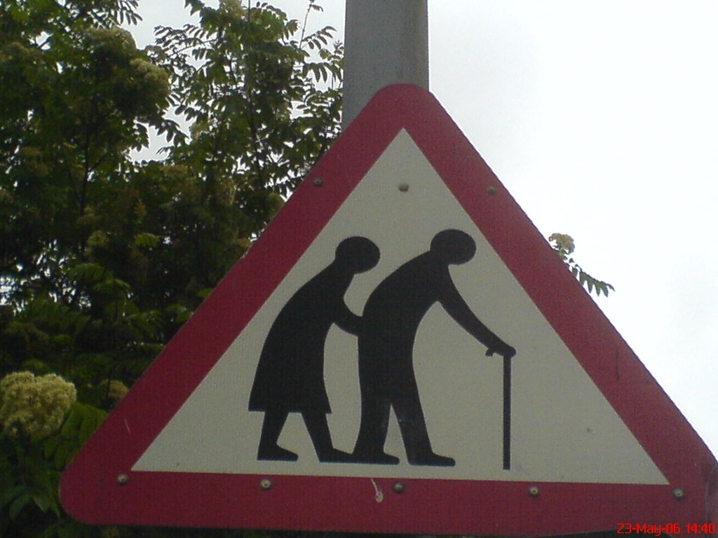 A street crossing sign with an outline of an older couple using a cane.