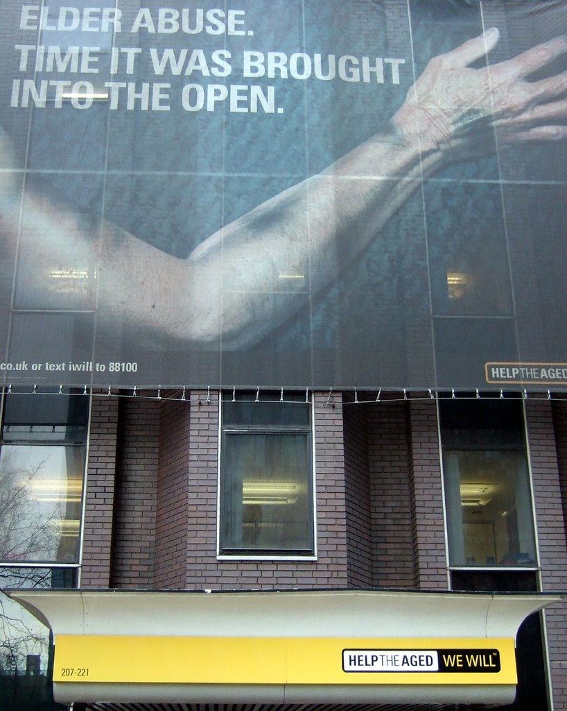 Picture of a billboard public service announcement showing a older adults bruised arm with the caption, "Elder abuse.  Time it was brought into the open."