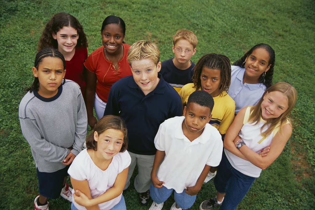 Group of kids of varying backgrounds standing in a field, looking at the camera.