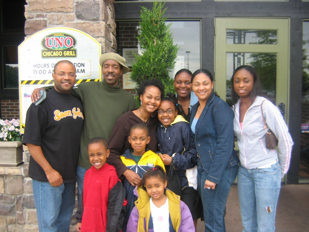Large African American or Black family posing outside of a restaurant.