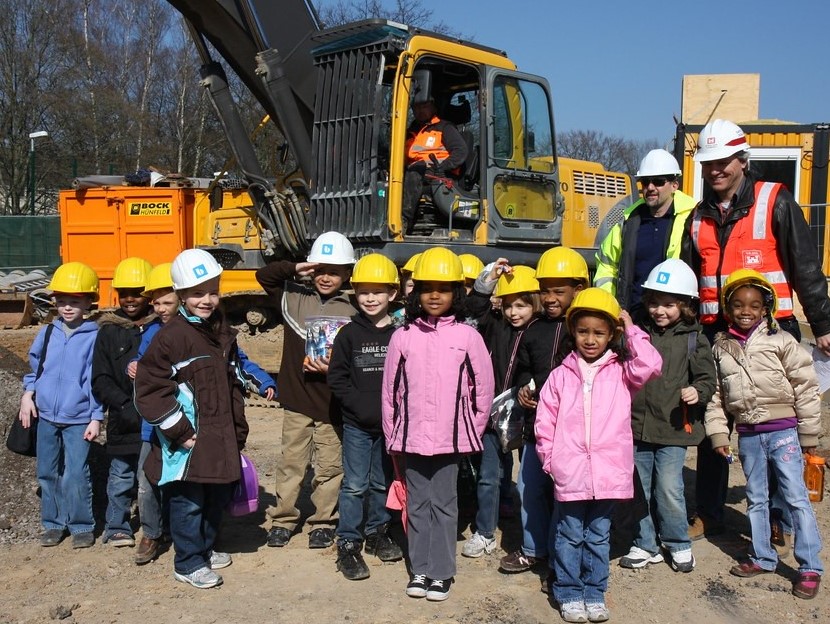 Group of Children standing in front of bulldozers on construction site