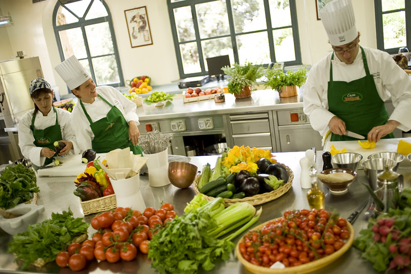 Three chefs preparing various vegetables in a kitchen