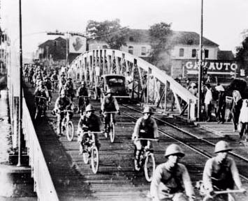 Photo of soldiers riding bikes across a bridge