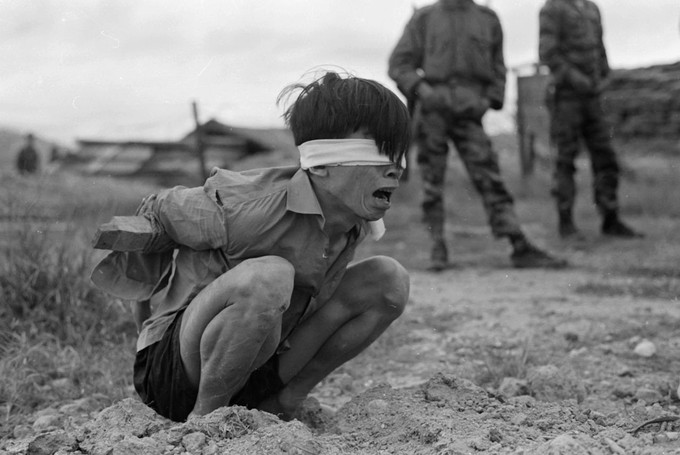 Photo of a bound, blind-folded, and kneeling young person