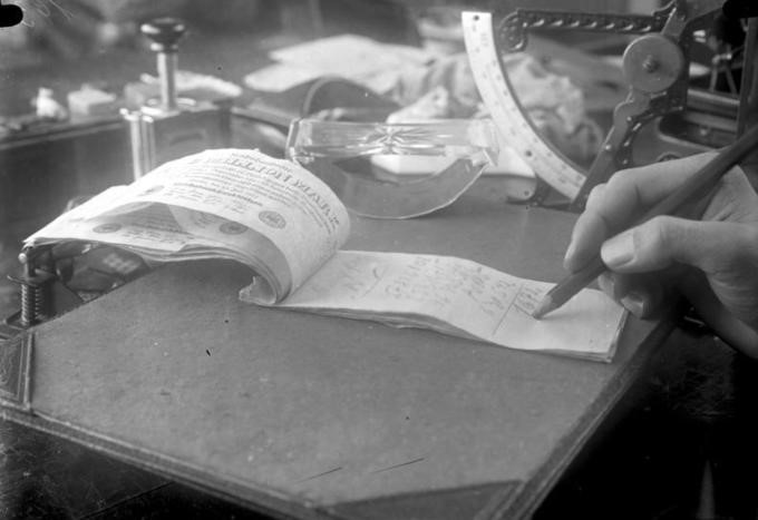 black and white photo of paper and hand holding a pen