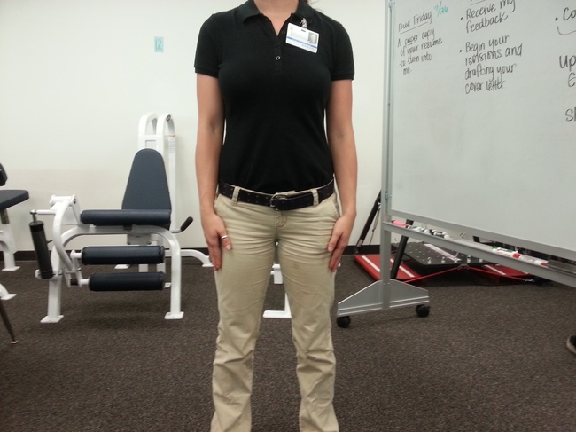 This shows generally accepted PT Aide attire in a private clinic, clothing that is professional and flexible for working: a polo shirt (tucked in), khakis, belt, and athletic shoes.